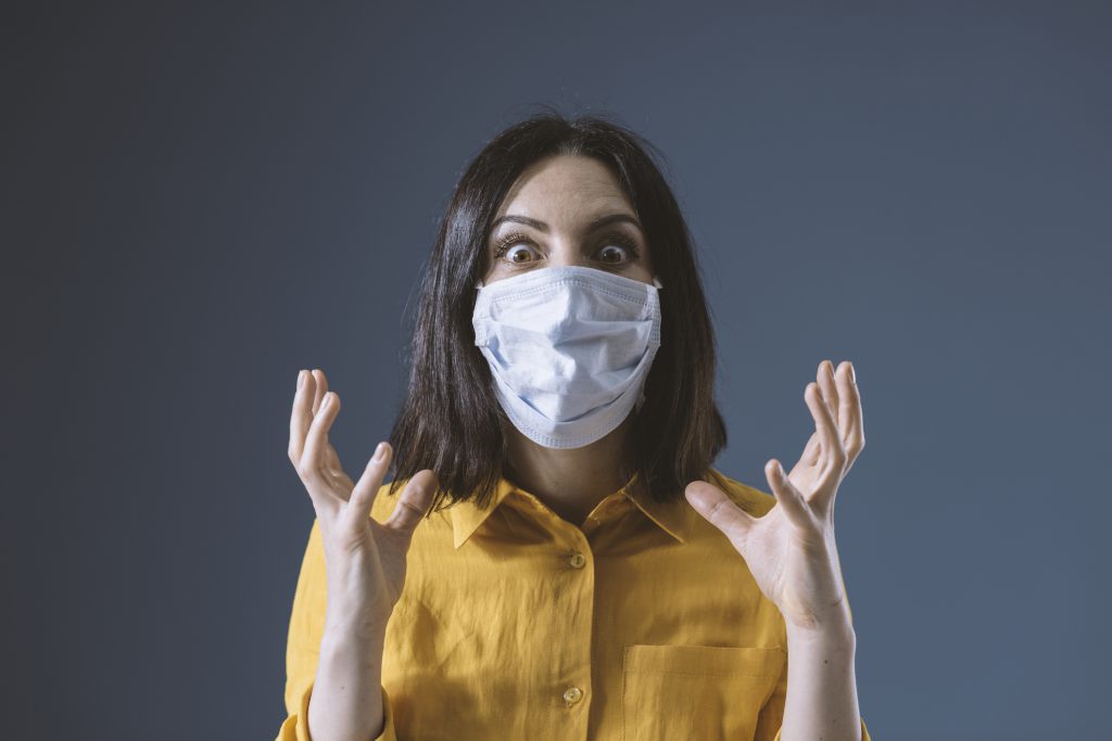 Panicked woman wearing a face mask against covid-19, she is scared and stressed